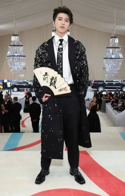 Embellished black formal coat styled with a fan
